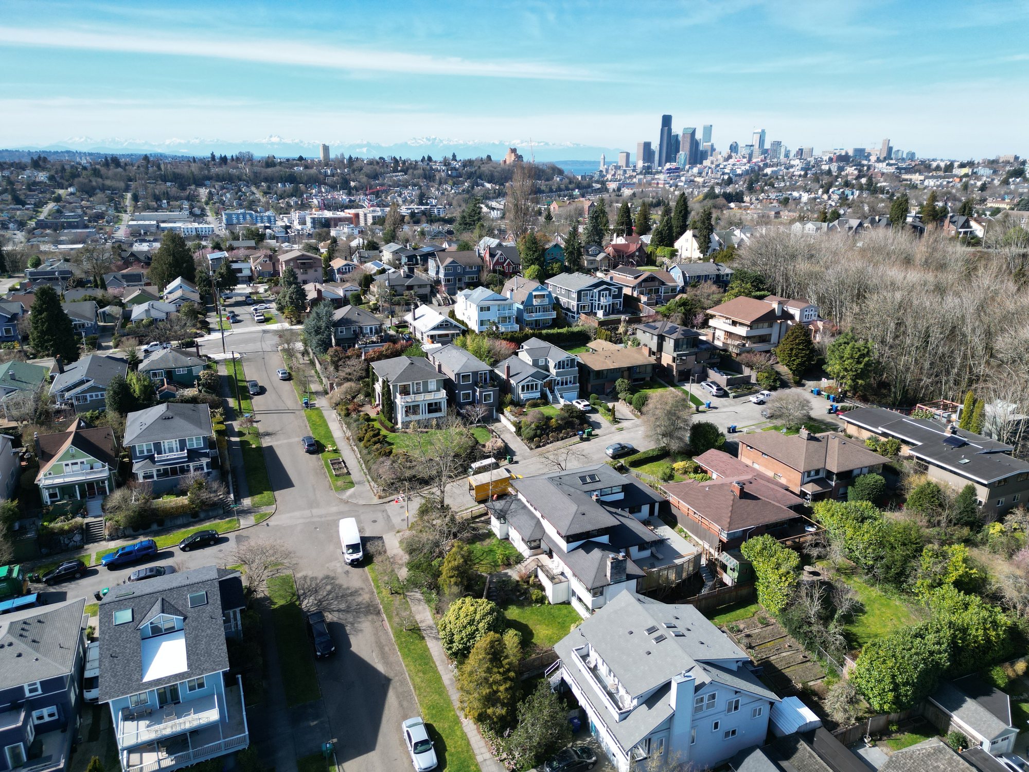 Aerial drone view of Plum St. in Seattle's Central District, with the downtown skyline and Olympic Mountains beyond
